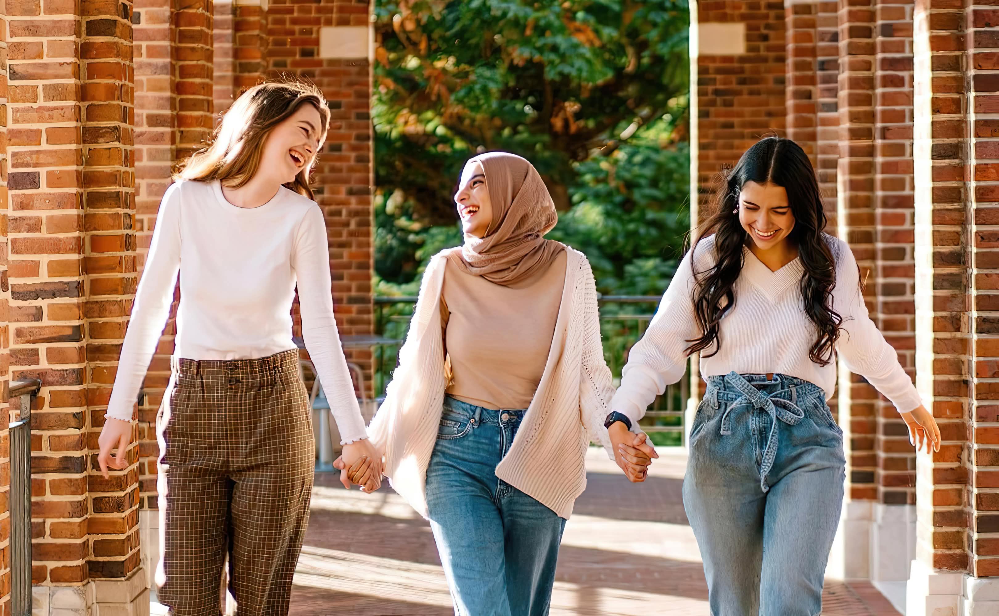 Pi Beta Phi member walking down outside corridor holding hands and smiling