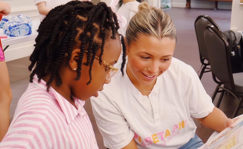 Pi Beta Phi sorority member helping out child.
