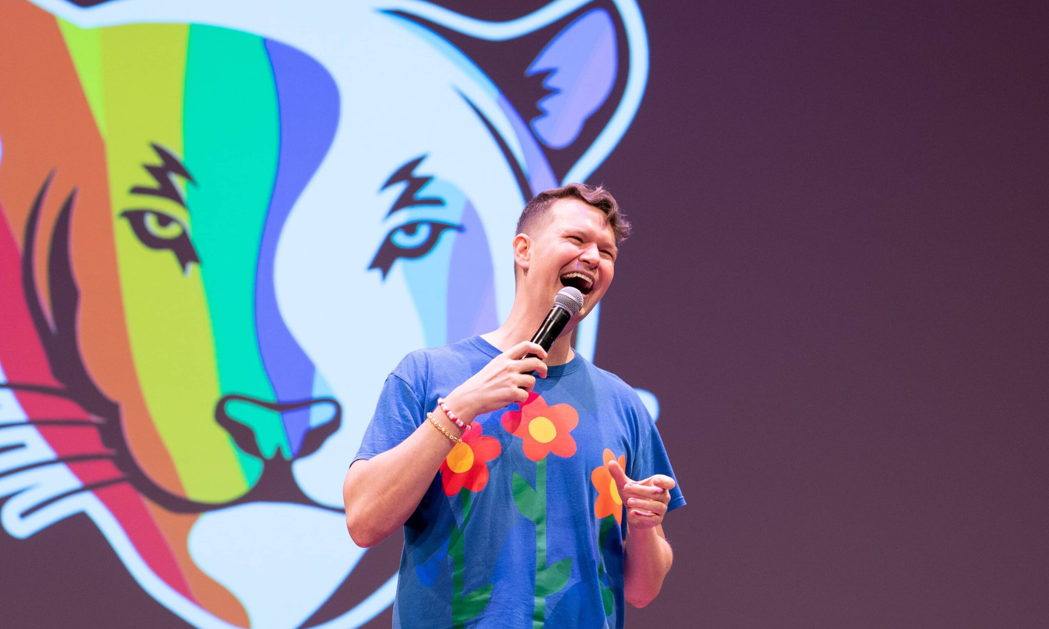PUA Every Voice client image of speaker standing in front of Every Voice tiger logo on projector