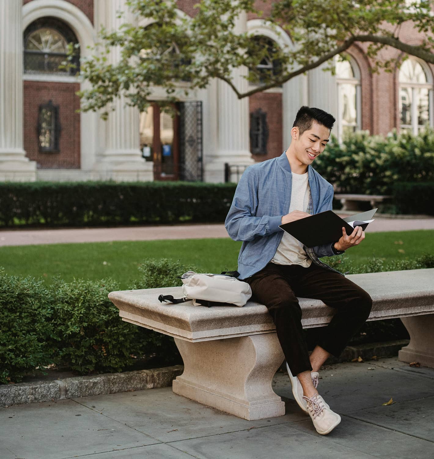 Student sitting outside on a bench reading a book