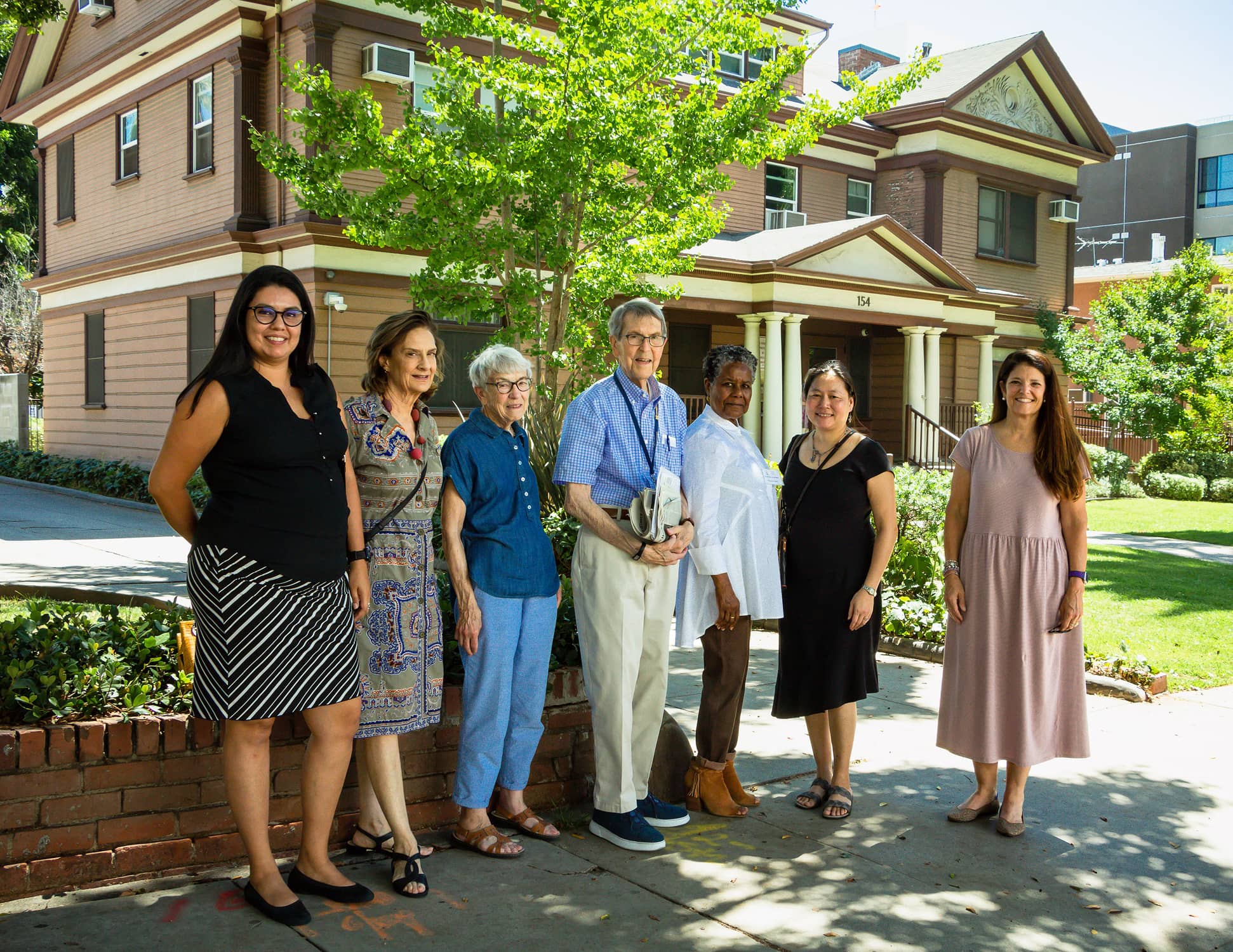 Group of people standing in front of a house smiling for a picture.