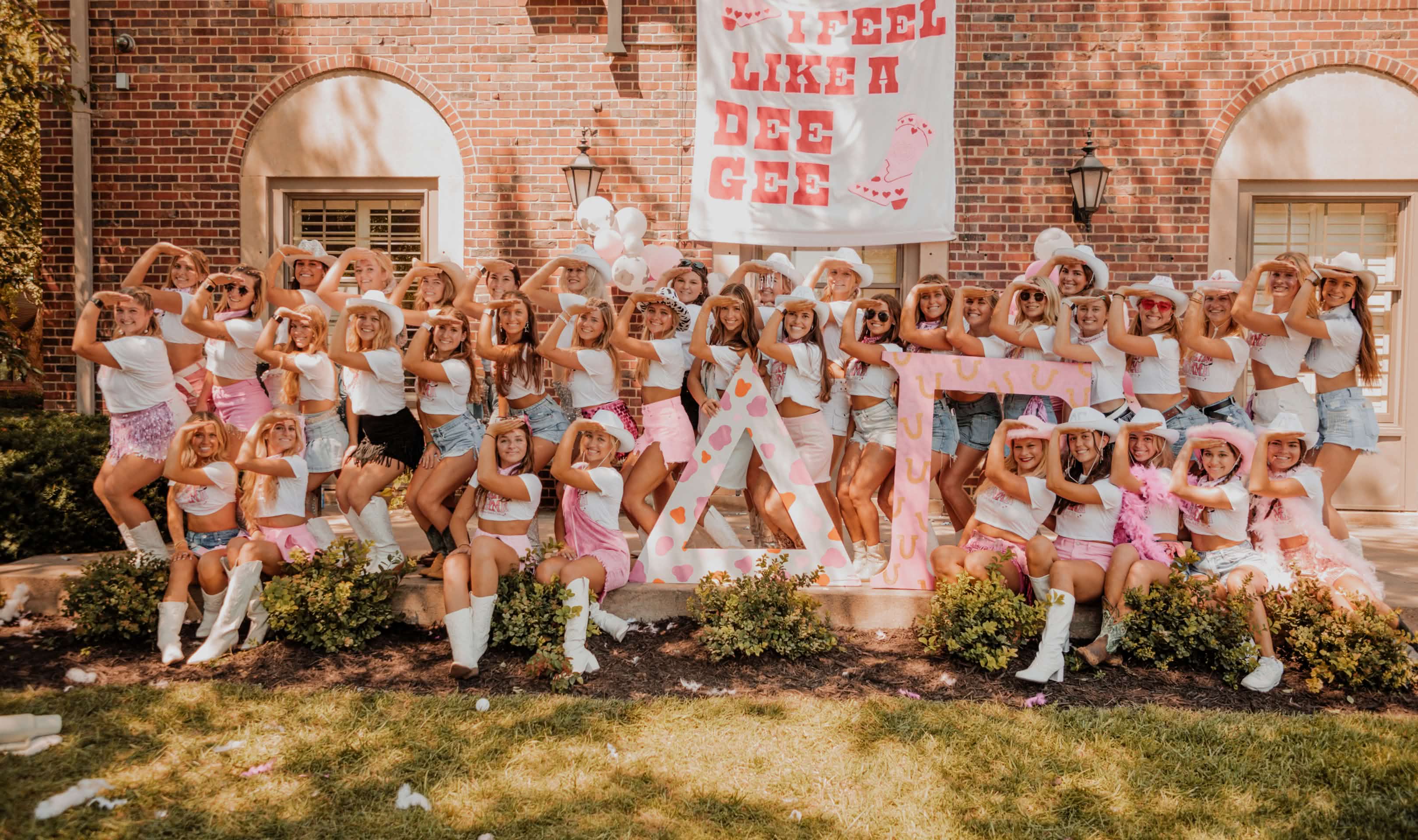 Delta Gamma Chapter posing for a photo infront of house wearing pink