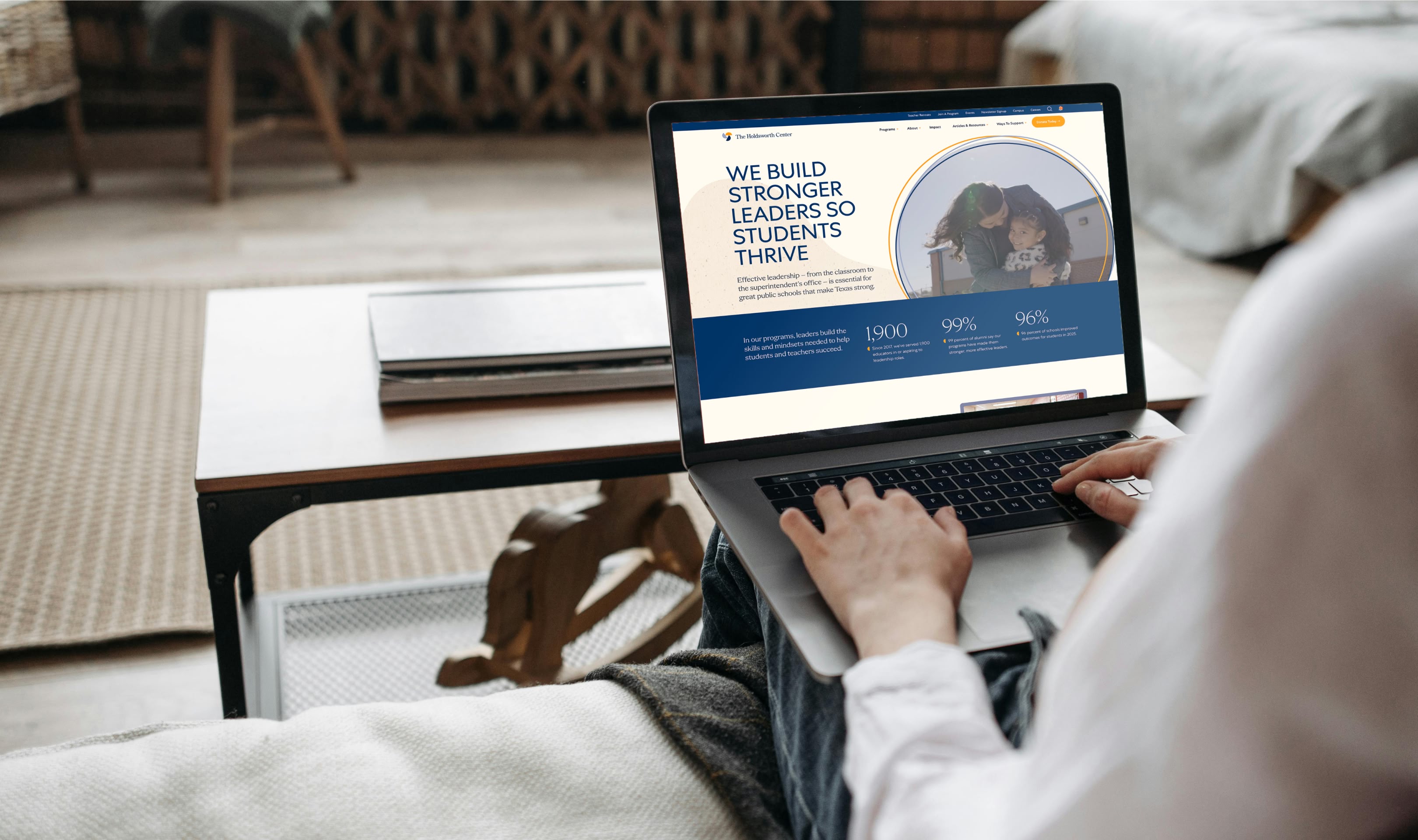 A person sits on a sofa using a laptop displaying a website with the text 