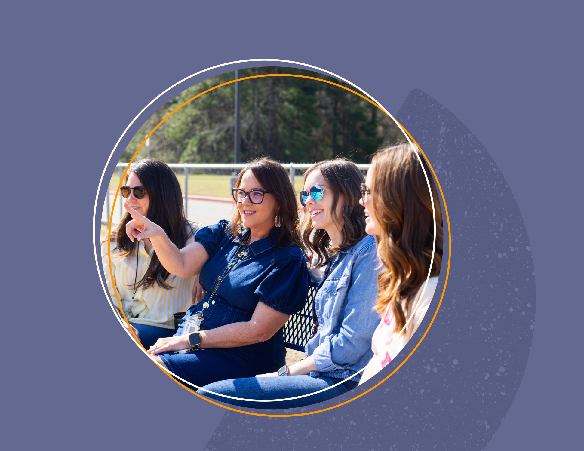 A group of four women sit on a bench outdoors, enjoying a sunny day. One points forward, all smiling and wearing sunglasses, creating a light-hearted mood.