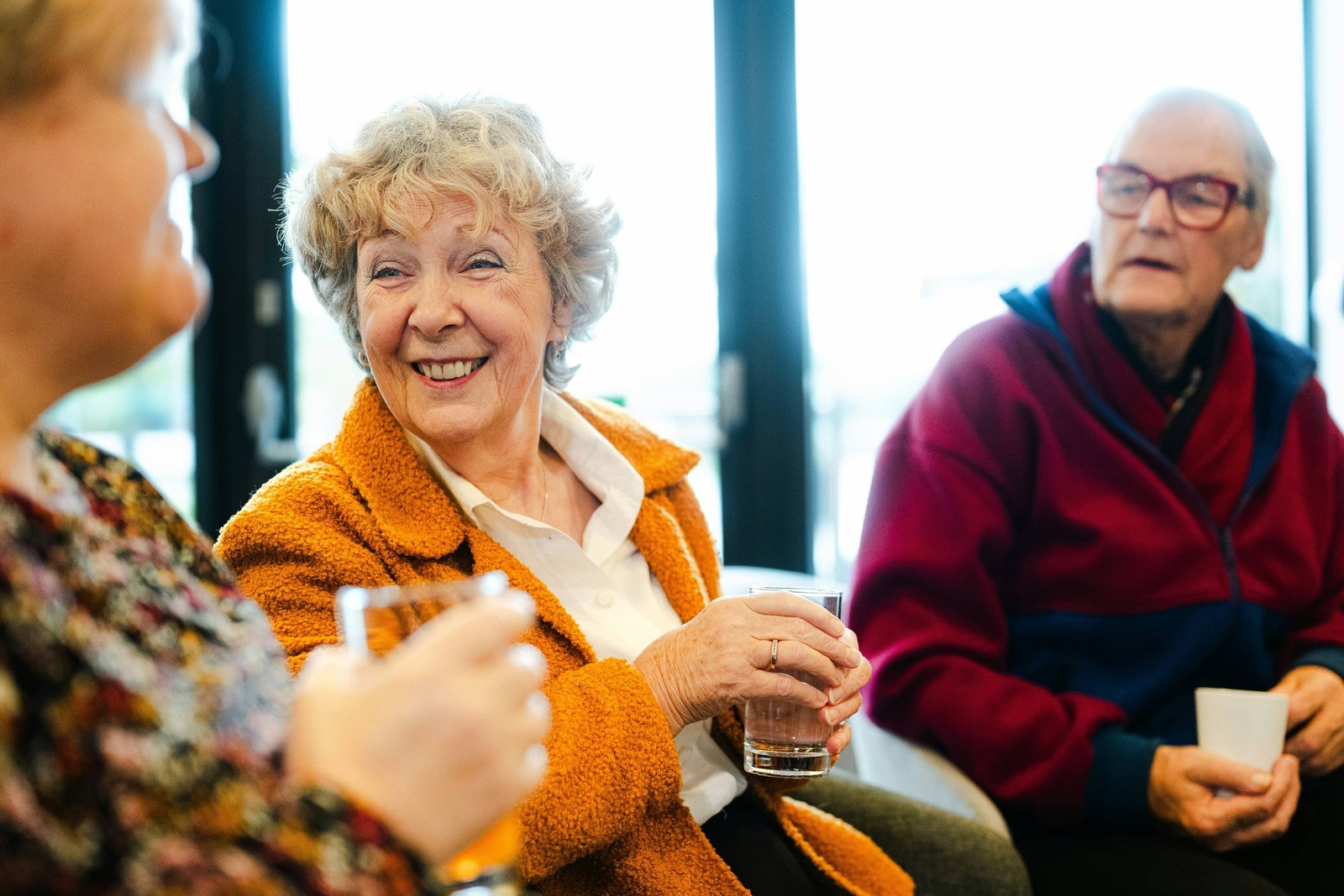 Two older adults laughing and talking during a community gathering, representing the vibrant, active audiences nonprofit organizations serve.