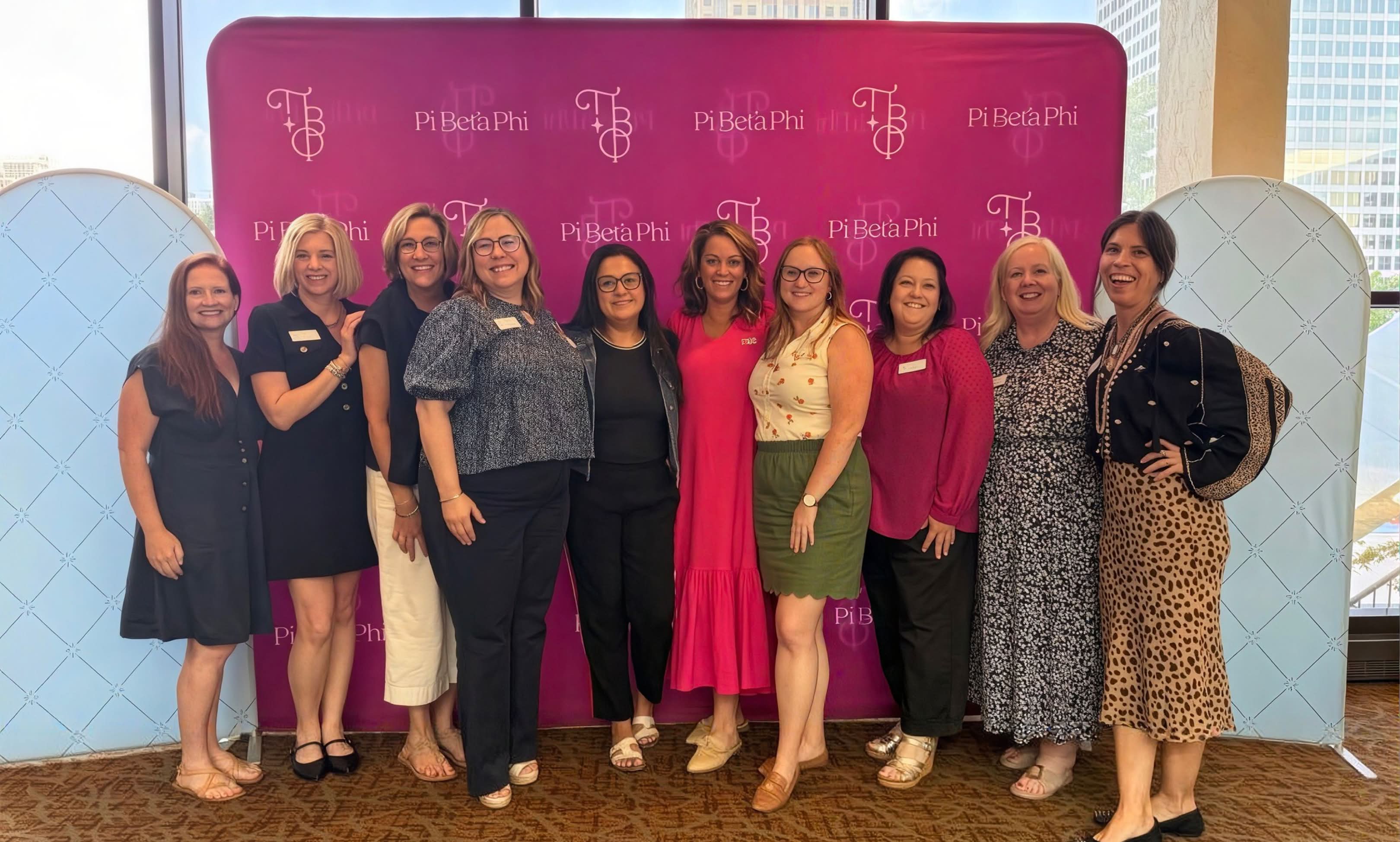 Pi Phi alumni and network members gathered at an event in front of a branded step-and-repeat banner.