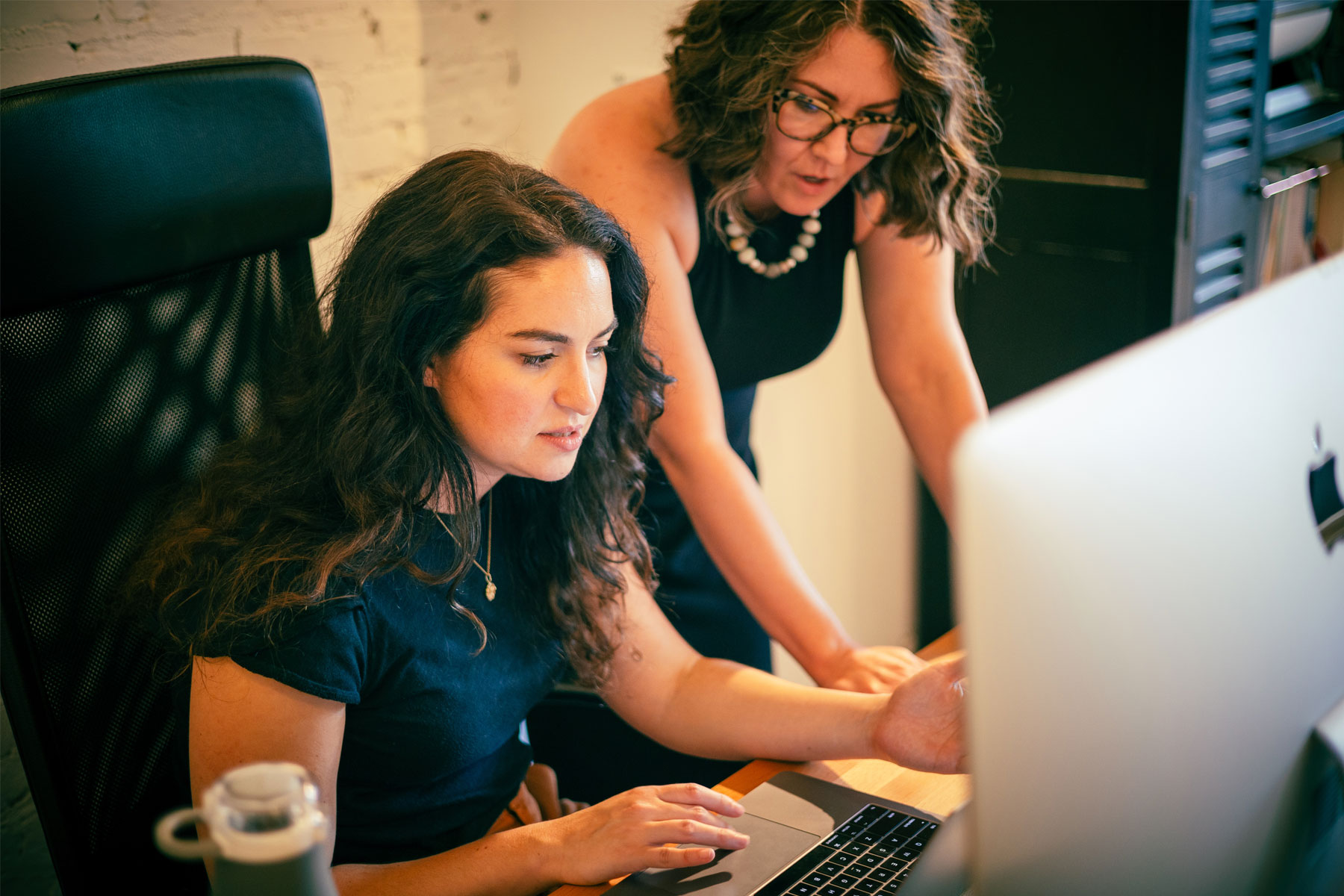Two women collaborating together on a design project at a computer